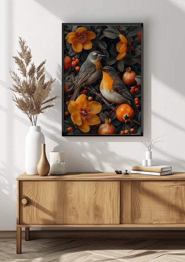 Een ingelijst schilderij Vogels Tussen Oranje Bloemen En Bessen van CollageDepot met twee vogels tussen oranje bloemen en vruchten hangt aan een witte muur, ondersteund door een magnetisch ophangsysteem. Hieronder staat een houten kast met twee witte vazen en een stapeltje boeken. Het decor is voorzien van neutrale tinten en een eenvoudige, moderne esthetiek.,Zwart