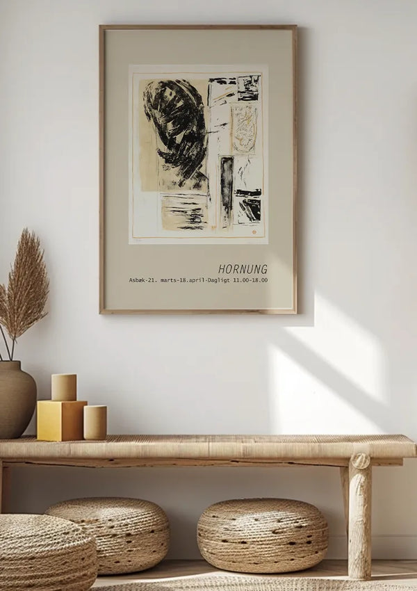 Een minimalistische kamer met een ingelijst abstract kunstwerk op een witte muur boven een lichthouten bank. Op de bank staat een vaas met gedroogde planten en drie op elkaar gestapelde cilindervormige kaarsen. Onder de bank staan twee geweven poefs. Zonlicht creëert schaduwen op de muur, wat de elegantie van het CollageDepot Tekst Hornung Schilderij versterkt.,Lichtbruin