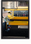Een ingelijste foto, perfect als wanddecoratie, toont het achteraanzicht van een gele Porsche 911 GT3 RS-sportwagen. De afbeelding toont de auto geparkeerd in een stadsstraat en benadrukt de opvallende achterspoiler en het strakke ontwerp. Verbeter uw ruimte moeiteloos met het Gele Porsche GT3 RS Schilderij van CollageDepot.,Zwart-Zonder,Lichtbruin-Zonder,showOne,Zonder