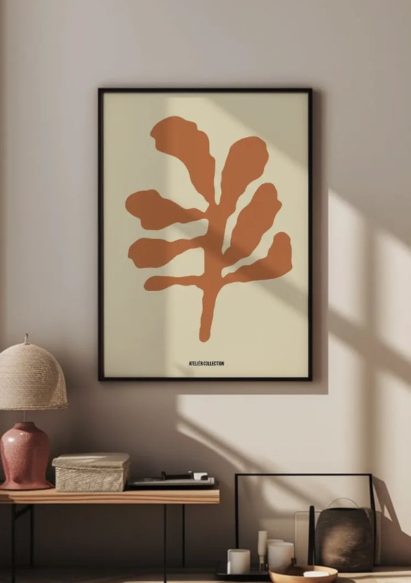 Een minimalistisch kunstwerk met een abstract bruin blad uit de bestsellerscollectie van CollageDepot hangt aan een beige muur en werpt een schaduw van het zonlicht. In de buurt rusten een lamp en decoratieve voorwerpen op een oppervlak.,Zwart