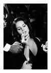 Een zwart-witfoto van een vrouw met golvend haar en donkere kleding die op het punt staat een sigaret op te steken. Verschillende handen houden aanstekers om haar heen vast. Op de achtergrond zijn personen in militaire uniformen te zien, waardoor een dramatische en elegante sfeer ontstaat. Perfect als wanddecoratie met een magnetisch ophangsysteem, de Glamorous Lana del Rey rokend van CollageDepot legt dit tafereel prachtig vast.