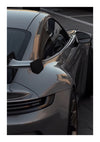 Close-up van een slanke, donkergrijze sportwagen geparkeerd in een schaduwrijk gebied, waarbij de vloeiende lijnen en glanzende carrosserie worden benadrukt met de bestuurderszijdespiegel en de deur in focus, is een beschrijving van de bestsellers van CollageDepot.-