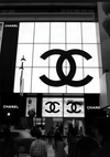Een grote CollageDepot-winkel die 's avonds verlicht is, met het iconische ab 019 - zwart-wit-logo op de gevel.-