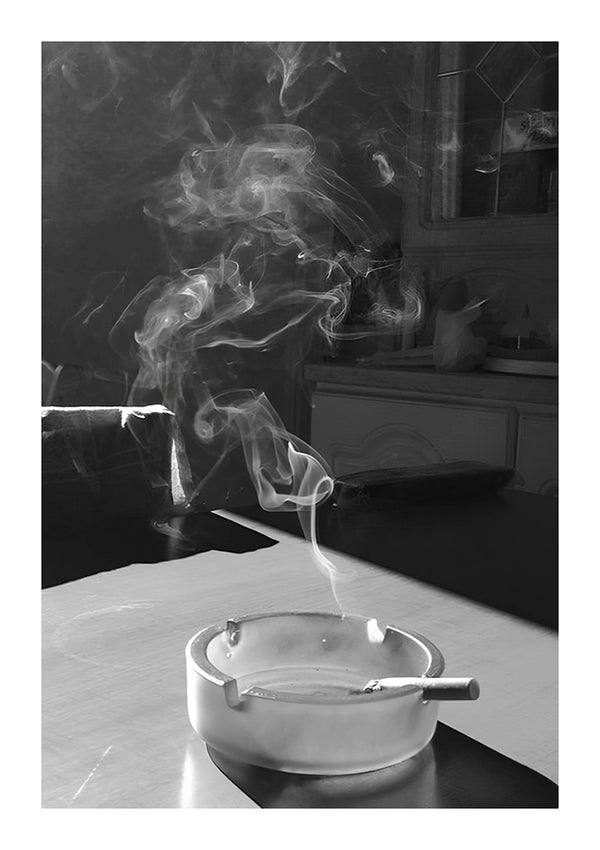 Zwart-wit kunstposter van rook die opstijgt uit een sigaret die in een asbak op een tafel is achtergelaten, terwijl zonlicht door een raam stroomt en schaduwen werpt met de ab 060 - zwart-wit van CollageDepot.-