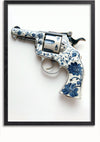 Afbeelding van een decoratieve revolver met een sierlijk blauw-wit bloemmotief, tegen een effen witte achtergrond. De revolver is gevat in een eenvoudig zwart frame, waardoor een unieke wanddecoratie ontstaat. Dit is het Delfts Blauw Revolver Schilderij van CollageDepot.,Zwart-Zonder,Lichtbruin-Zonder,showOne,Zonder