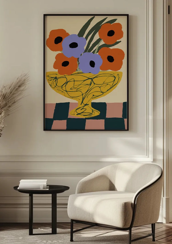 Een minimalistische kamer met een ingelijst schilderij van kleurrijke bloemen in een vaas aan de muur, boven een kleine, moderne fauteuil. Naast de stoel staat een ronde, zwarte bijzettafel met een stapel witte boeken. De muur en het decor zijn in neutrale tinten, wat de elegante wanddecoratie Kronkelende Lijn Vaas Schilderij van CollageDepot benadrukt.