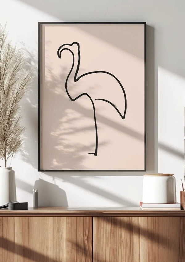 Een minimalistische line art poster van een flamingo in een zwarte lijst, of Flamingo Schets Schilderij van CollageDepot, hangt aan een witte muur. Daaronder staat een houten kast met daarin een witte vaas met pampasgras, een klein wit schaaltje en diverse decoratieve voorwerpen. De scène wordt helder verlicht door natuurlijk licht.,Zwart