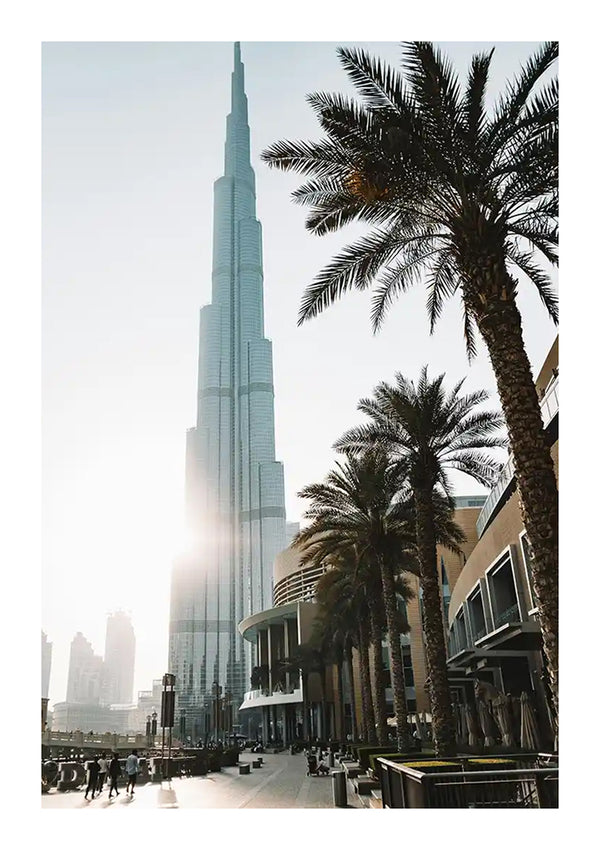 Een zonovergoten uitzicht op de Burj Khalifa die uittorent boven een straat vol palmbomen en kleine gebouwen, met mensen en auto's zichtbaar op de voorgrond met de baa 004 - landen en steden van CollageDepot.-