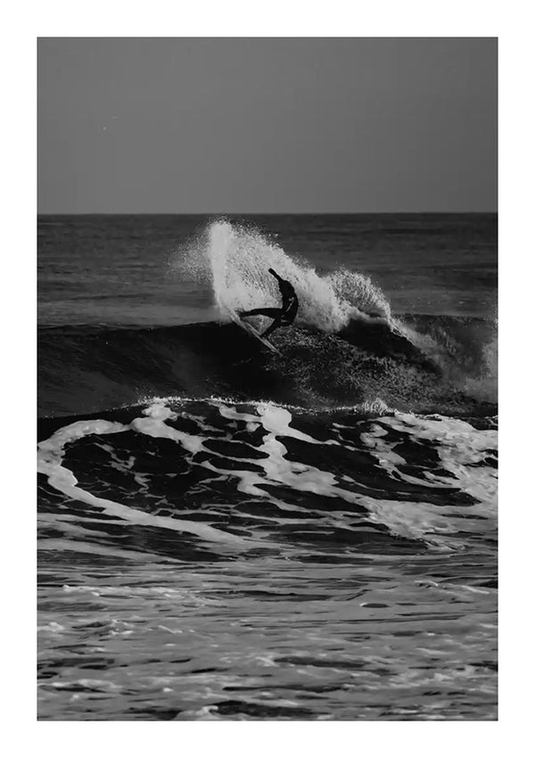 Een zwart-wit Surfen Op Een Grote Golf Schilderij van een persoon die surft op een grote golf in de oceaan. De surfer berijdt de golf en er is waternevel zichtbaar nabij de surfplank. Dit prachtige stukje CollageDepot wanddecoratie legt de ruwe, woelige zee met ongelooflijke details vast.-