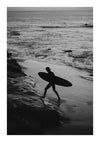 Een zwart-witafbeelding toont een surfer die een surfplank draagt terwijl hij langs een strand loopt. Golven beuken op de achtergrond op de kust en de lucht is bewolkt. Het silhouet van de surfer is duidelijk zichtbaar tegen de lichtere golven en het zand, waardoor hij perfect is voor wanddecoratie met een CollageDepot Surfer Uit Het Water Schilderij en een magnetisch ophangsysteem.-
