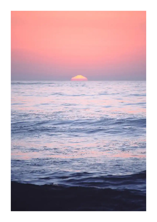 Een sereen uitzicht op de oceaan tijdens zonsondergang, vastgelegd in een prachtige Opname Tijdens zonsondergang Schilderij van CollageDepot. De zon is gedeeltelijk zichtbaar aan de horizon en de lucht is getint met roze en oranje tinten. Het kalme water weerspiegelt de kleuren van de lucht, waardoor het een perfect wanddecoratie voor je huis is.-