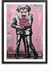 Op een ingelijst Love is all-schilderij van CollageDepot zijn twee politieagenten in zwart-wituniformen te zien die elkaar op de lippen kussen. Eén houdt een boeket roze rozen vast en op de achtergrond een overwegend roze muur met wat graffiti en verfdruppels, eenvoudig te monteren met een magnetisch ophangsysteem.