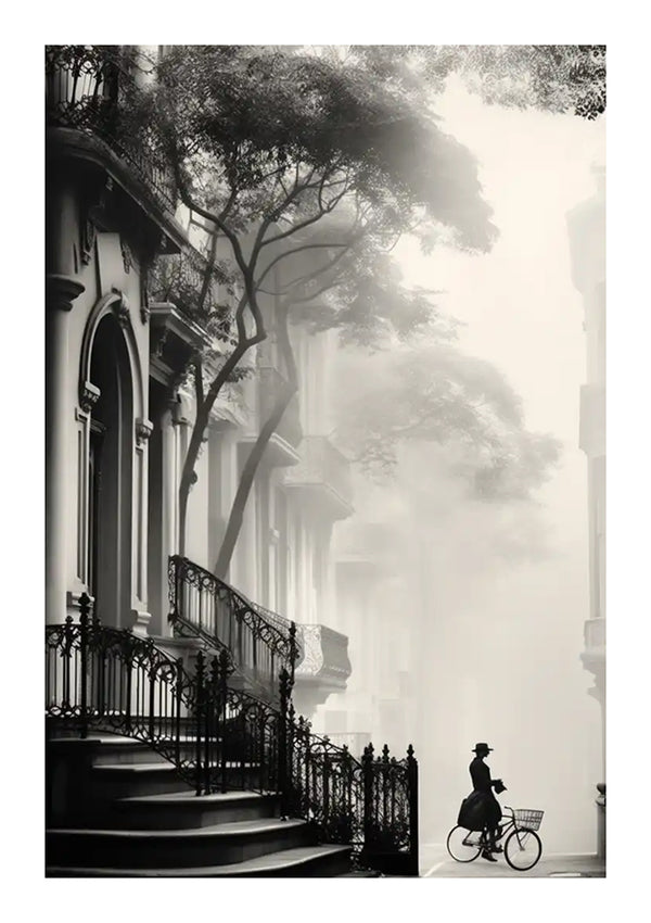 Een zwart-witafbeelding toont een mistige straat vol sierlijke gebouwen. Een persoon met een hoed op fietst met een mandje over het trottoir. Hoge, slanke bomen met spreidende takken zijn zichtbaar te midden van de architectuur. Het tafereel maakt deel uit van de cbb 003 - vintage collectie van CollageDepot.-