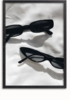 Een foto van twee paar zwarte zonnebrillen met dikke rechthoekige monturen, diagonaal en evenwijdig aan elkaar geplaatst op een wit oppervlak. De zonnebrillen werpen schaduwen, benadrukken hun vorm en ontwerp, waardoor ze een perfecte wanddecoratie lijken. Dit stuk is verkrijgbaar als het Twee Zwarte Zonnebrillen Schilderij van CollageDepot.,Zwart-Zonder,Lichtbruin-Zonder,showOne,Zonder