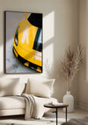 Aan een beige muur in een minimalistische woonkamer hangt een ingelijste foto van een Prachtige gele Ferrari 488 Pista met zwarte strepen. De CollageDepot wanddecoratie bestaat uit een lichte bank met een deken, een ronde salontafel en een hoge vaas met gedroogde planten. Natuurlijk licht vult de ruimte.,Zwart
