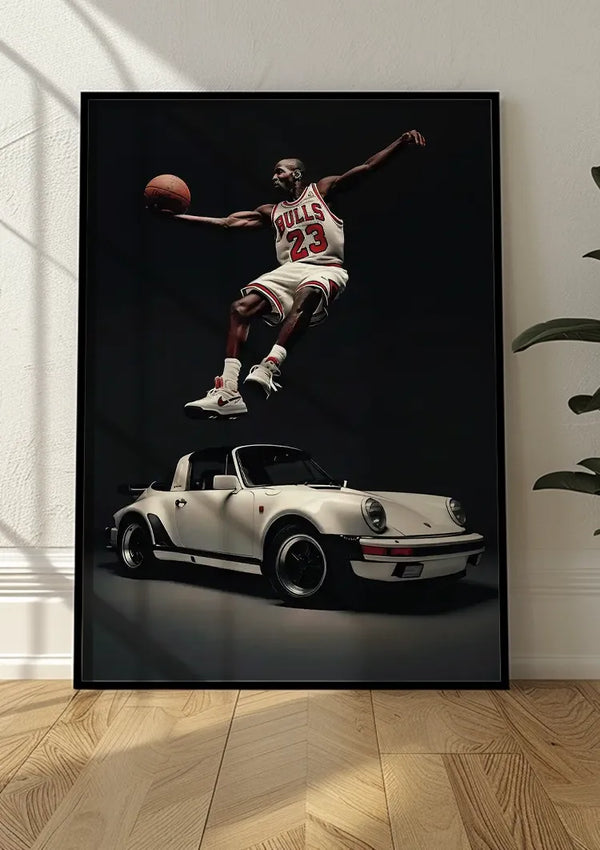 Een ingelijst CollageDepot The Dream Team Schilderij staat op een houten vloer tegen een witte muur. De poster toont een basketbalspeler in de lucht, gekleed in een trui met het nummer 23, terwijl hij een basketbal vasthoudt boven een klassieke 911 cabrio. Aan de rechterkant is gedeeltelijk een plant zichtbaar.,Zwart