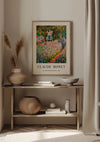 Een ingelijst CollageDepot Claude Monet The Artist's Garden in Giverny Schilderij hangt boven een houten consoletafel. Op de tafel staat een vaas met gedroogd gras, een kom, een geweven mand en boeken. Neutraal gekleurde gordijnen en zacht, warm licht vullen de kamer en creëren een serene sfeer.,Lichtbruin