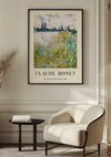 Aan een witte muur hangt een ingelijst Claude Monet Île Aux Fleurs Nabij Vétheuil Schilderij van CollageDepot van een landschap met bloemen en een rivier. Onder het schilderij staat de tekst "Claude Monet" en "Le Bas-Fresne, River View" samen met het jaartal "1890". Op de voorgrond staan een beige fauteuil en een klein zwart tafeltje, waardoor een elegante wanddecoratie ontstaat.,Zwart