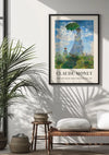Een zonovergoten muur toont een ingelijste vrouw van Claude Monet met een parasol - Schilderij Madame Monet en haar zoon van CollageDepot, elegant gemonteerd met behulp van een magnetisch ophangsysteem. Onder het schilderij is een rieten bank versierd met kussens en manden. Een potplant werpt schaduwen op de muur, wat de serene sfeer versterkt.,Zwart