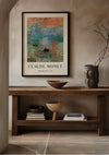 Een ingelijste Claude Monet Impression, Sunrise Schilderij van CollageDepot wordt opgehangen met behulp van een magnetisch ophangsysteem boven een houten consoletafel met diverse decoratieve items, waaronder houten schalen en vazen, en een kleine stapel boeken op de onderste plank, in een moderne, neutrale tint. kamer.,Zwart