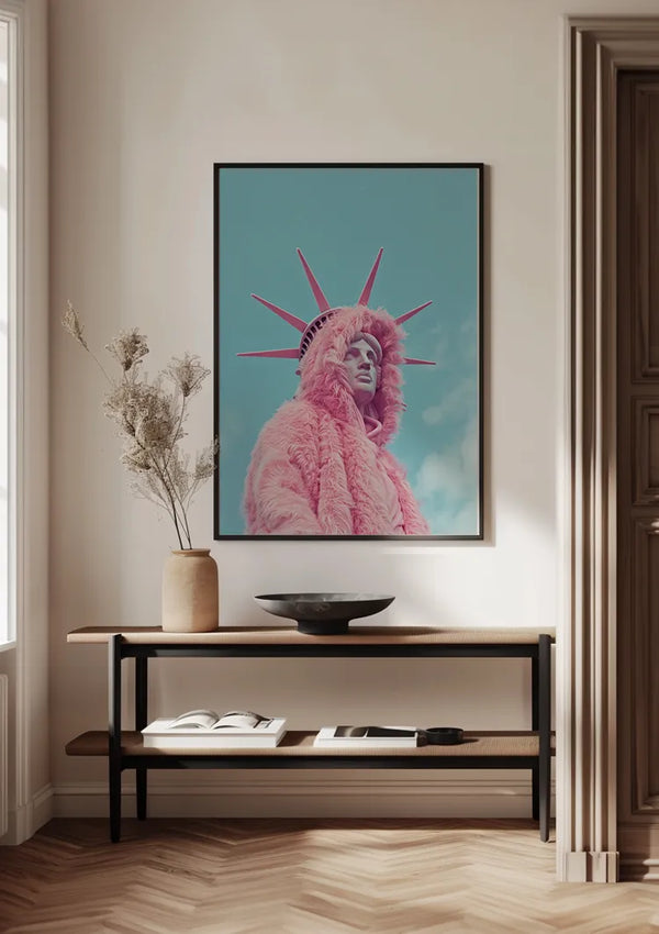 Een ingelijst Vrijheidsbeeld met pluizig roze hoodie-schilderij van CollageDepot van een persoon in een roze bontjas in de stijl van het Vrijheidsbeeld hangt aan een muur boven een houten consoletafel. De console, versierd met een vaas met gedroogde planten, een open boek en een ondiepe zwarte kom, vormt een aanvulling op de parketvloer en het lichte, neutrale kleurenschema van de kamer.,Zwart