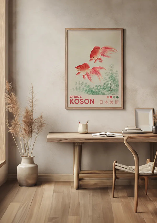 Een minimalistisch interieur met een houten bureau en stoel, een ingelijst O. Koson Goudvissen Schilderij van CollageDepot aan de muur met een magnetisch ophangsysteem, een potplant met hoog gras en een notitieboekje met een pen op het bureau. De setting heeft een rustige, natuurlijke esthetiek.,Lichtbruin