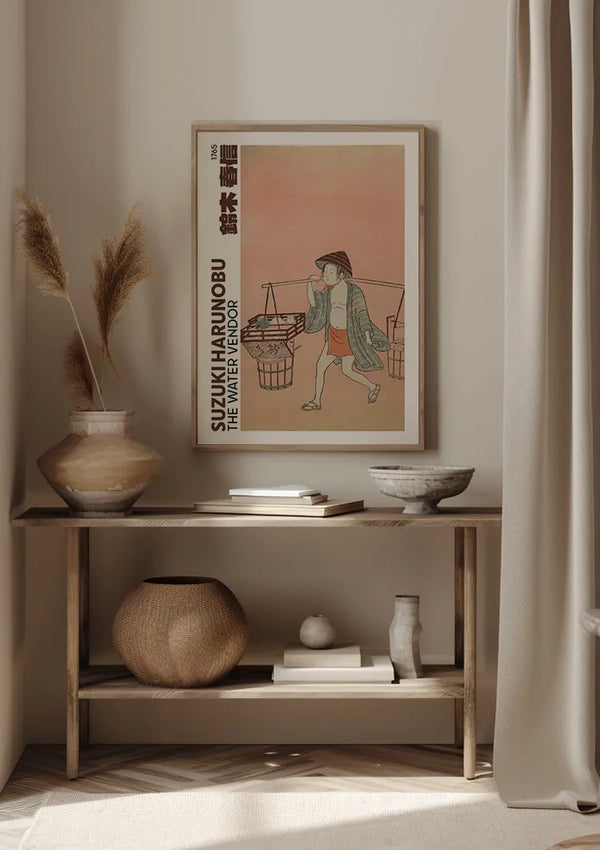 Het minimalistische interieur is voorzien van een ingelijst kunstwerk van Suzuki Harunobu met de titel "The Water Vendor" boven een houten tafel. Op de tafel staat een vaas met gedroogd pampagras, een kom en daaronder een geweven mand. Beige gordijnen omlijsten het tafereel en het S. Harunobu The Water Vendor Schilderij van CollageDepot is elegant opgehangen met behulp van een magnetisch ophangsysteem.,Lichtbruin