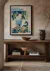 Een ingelijst CollageDepot K. Hokusai Yoro Waterfall In Mino Province Schilderij, een prachtige wanddecoratie, hangt aan een beige muur boven een houten consoletafel. Op de tafel staan decoratieve kommen, een keramische vaas en gestapelde boeken. Het omringende interieur is minimalistisch, met gedempte kleuren en een eenvoudige inrichting.,Zwart