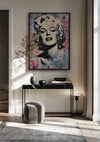 Een moderne woonkamer is voorzien van een zwartmarmeren consoletafel versierd met een vaas, plant en decoratieve items. Boven de tafel hangt een kleurrijk Marilyn Monroe Stijlvolle Popart Schilderij van CollageDepot van een vrouw met behulp van een magnetisch ophangsysteem. Beneden staat een kleine grijze poef en het licht stroomt naar binnen door een raam met lichte gordijnen.